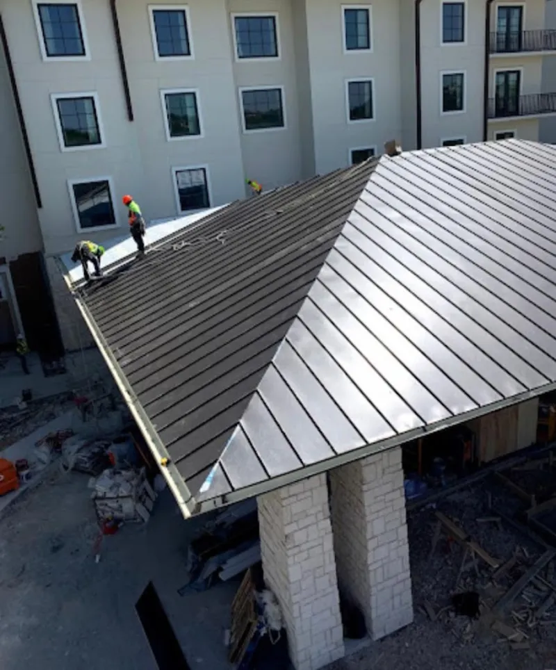 Crew installing standing seam metal roof panels on a commercial project in Harris